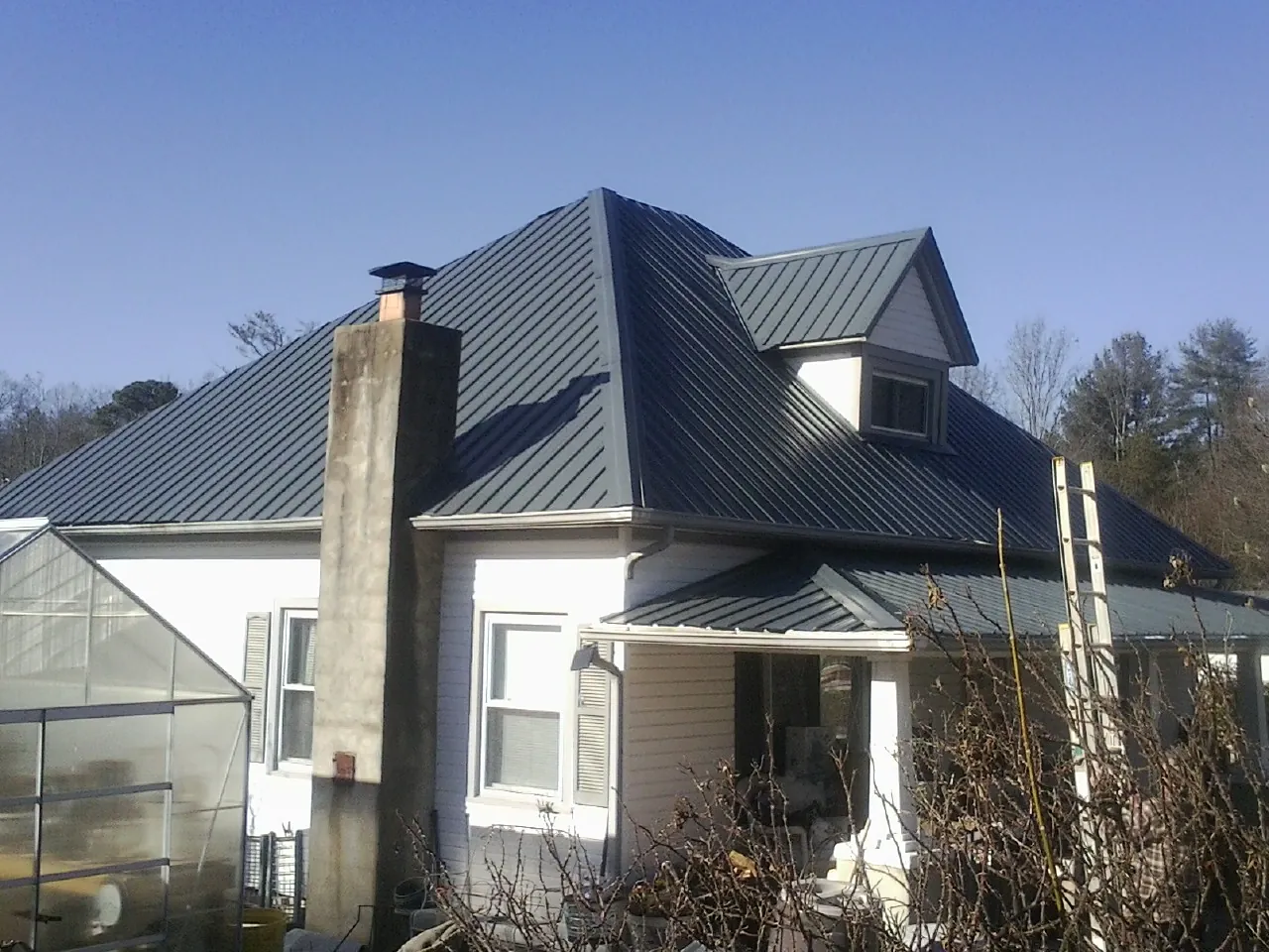 Dark blue standing seam metal roof on a white farmhouse with dormer — Slate & Tile Roof Repair by Roofing Brothers in Arkville