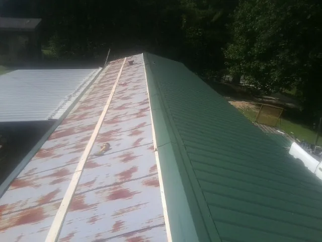 Old rusted panels beside newly installed green metal roofing — Wind Damage Roof Repair by Roofing Brothers in Arkville