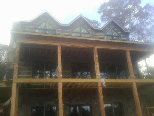 Dormers and porch framing on a large log home under construction — Roof Coating work by our crew in Arkville