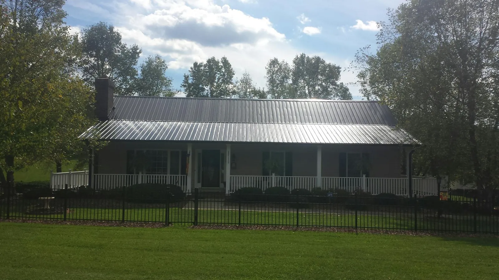 Gray metal roof on a brick ranch with a full width front porch — Gutter Guard Installation work by our crew in Arkville