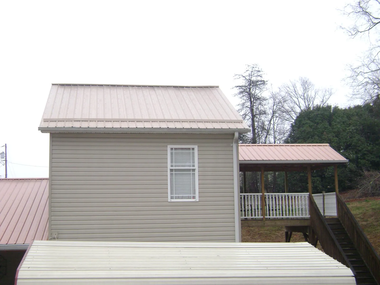 Tan metal roofs on a two story addition and attached porch, from a Roof Replacement job in Arkville