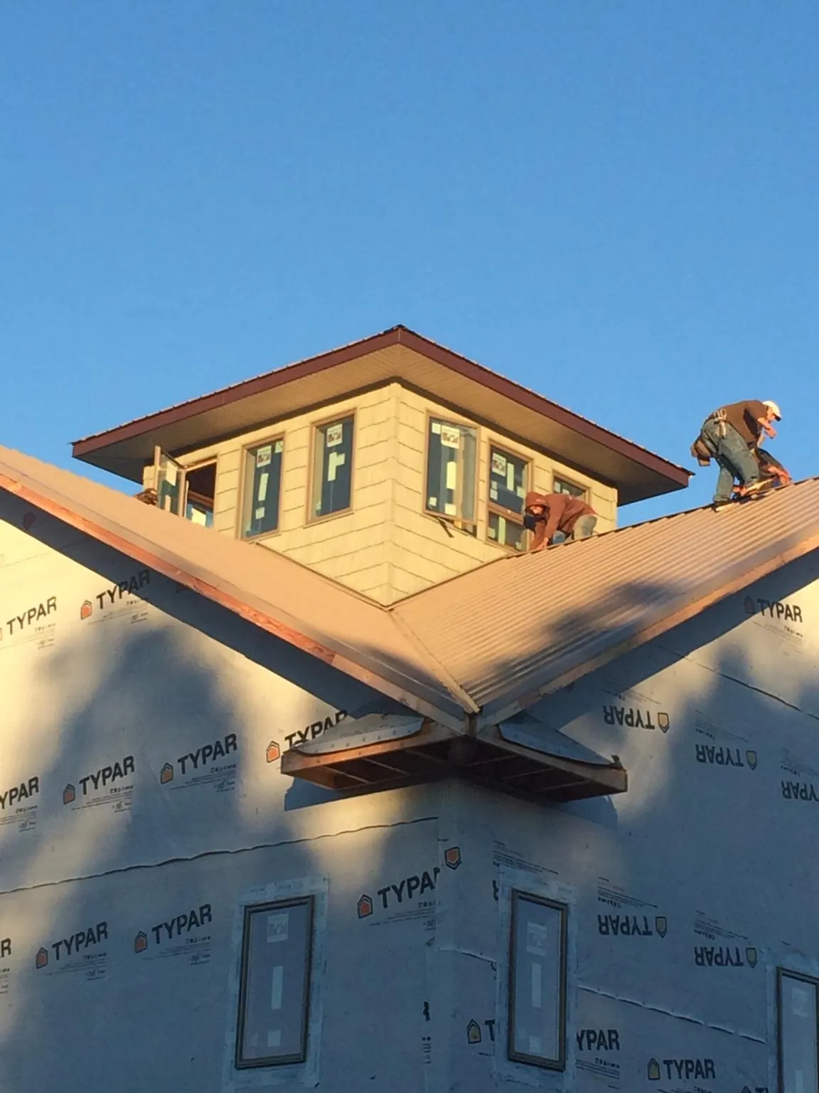 Roofers working around a rooftop cupola on a new metal roof at sunset — Roof Waterproofing in Arkville by Roofing Brothers